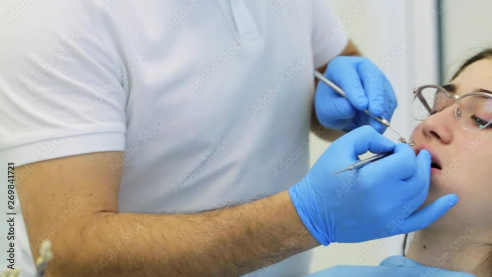 Dentist makes dental fillings for young woman patient, puts filling