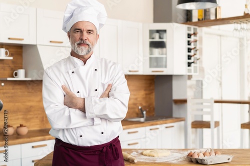 Attractive Caucasian chef standing with arms crossed in a restaurant kitchen