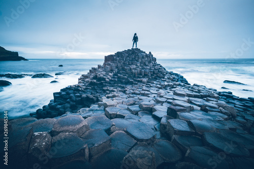 A person standing on the rocks by the sea at the Giant's Causeway, Northern Ireland.