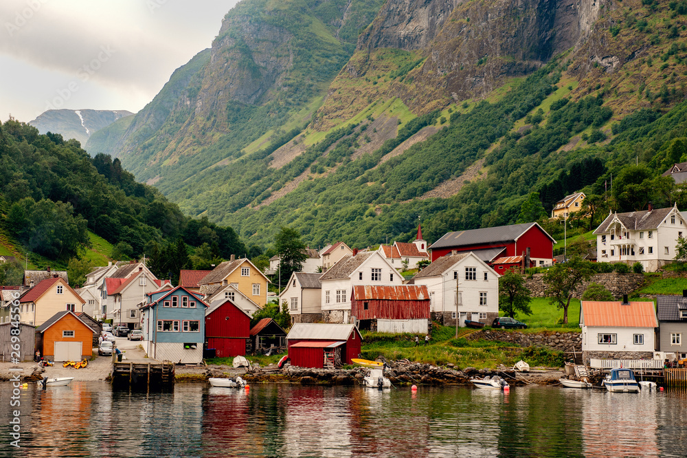 Fototapeta premium Small houses of the commune on the fjord, photographed from a sightseeing cruise ferry departing in summer from Flam, Norway