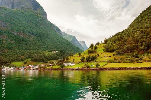 Small houses of the commune on the fjord, photographed from a sightseeing cruise ferry departing in summer from Flam, Norway
