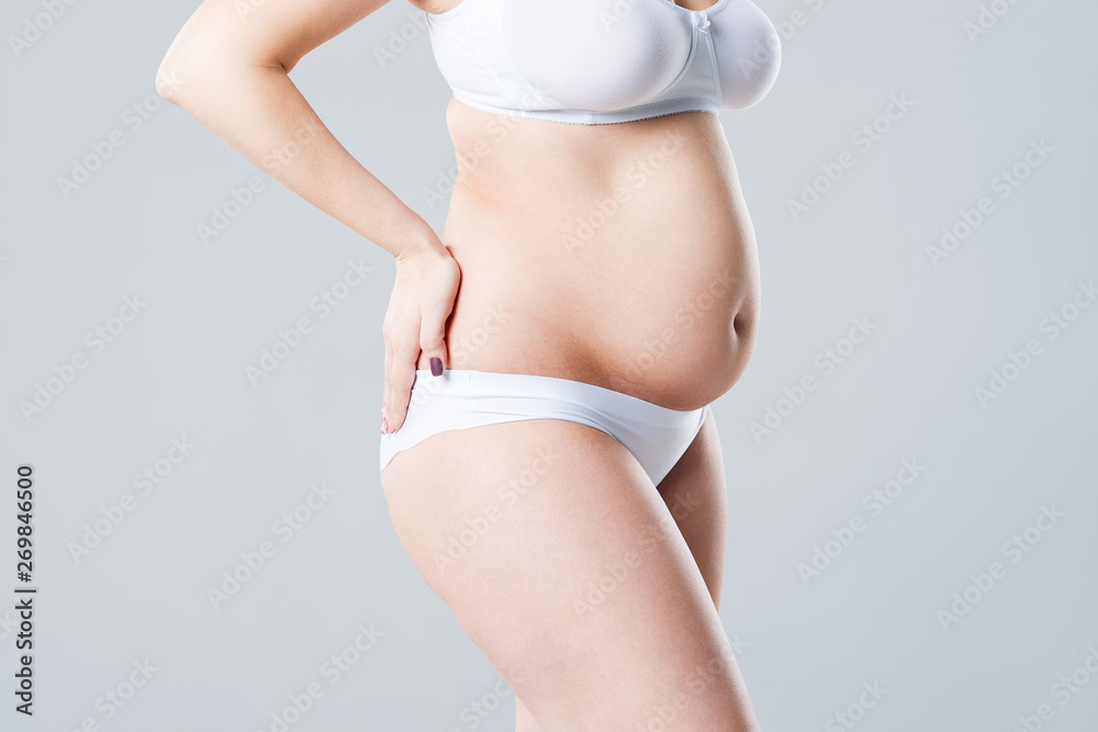 Fat woman with bloating, overweight female body on gray background - obrazy, fototapety, plakaty 