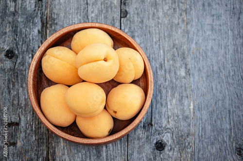 Ripe Golden apricots in wooden bowl on wooden background. Copy space