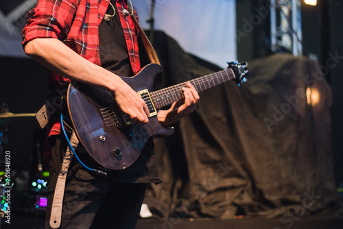 Electric guitar in the hands of a rocker. A man plays the guitar at a rock concert.