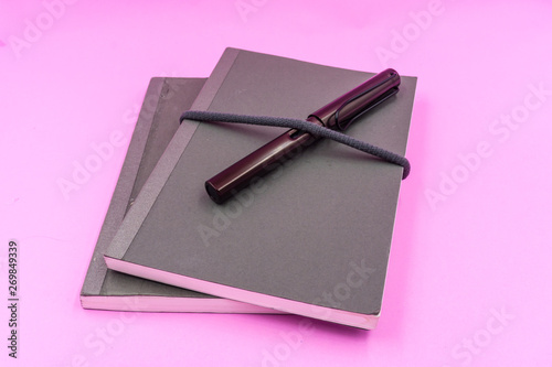 Gray Notebooks with dark brown Foutian pen on pink pastel background photo