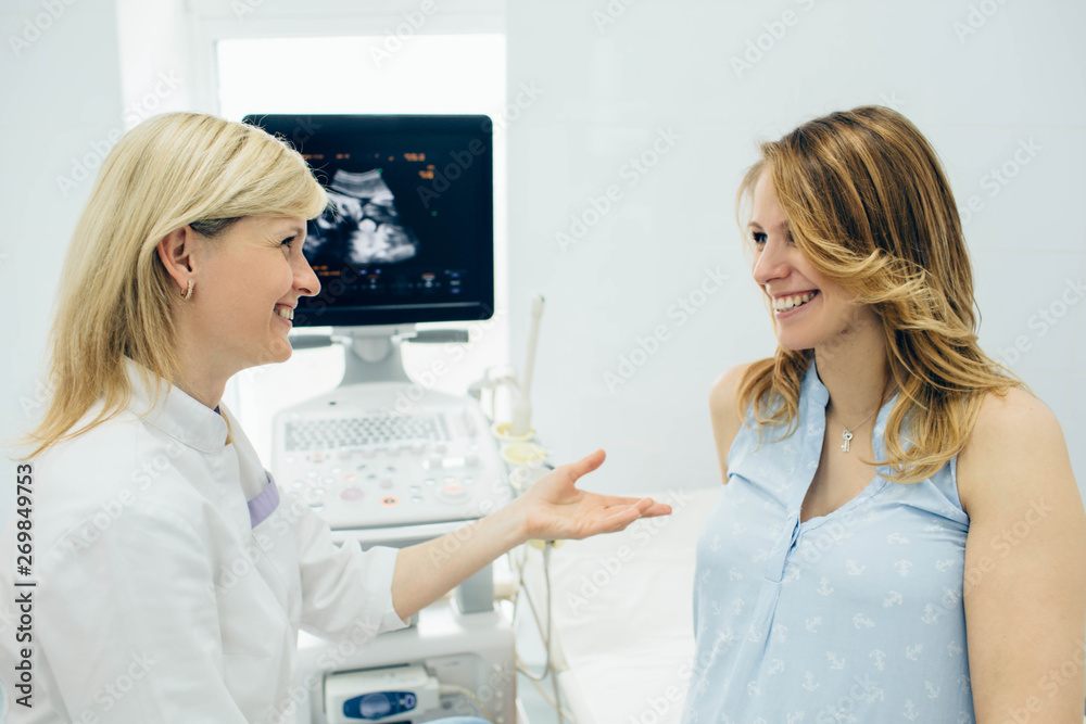 Smiling obstetrician talking with pregnant woman in clinic examination room. Consultation pregnancy Smiling obstetrician talking with pregnant woman in clinic examination room. Consultation pregnancy