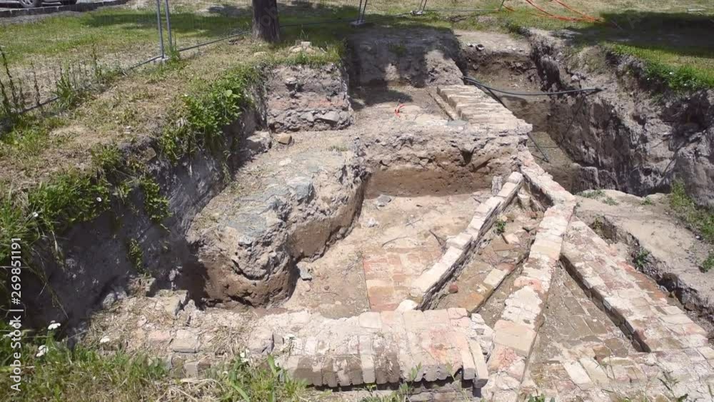 Archaeological site surrounded and protected by a protective metal fence of old Roman empire well or bathroom as historical archeology place and ruins Archaeological site surrounded and protected by a protective metal fence of old Roman empire well or bathroom as historical archeology place and ruins