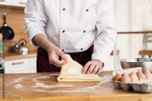 baker making bread , man hands , kneading a dough , cooking coat.