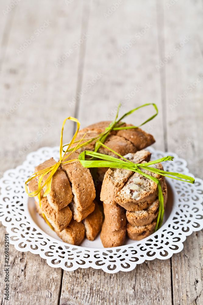 Fototapeta premium Fresh Italian cookies cantuccini with almonds stacked on white plate on ructic wooden table background.