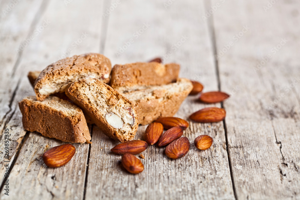 Fototapeta premium Fresh homemade Italian cookies cantuccini heap and almond seeds on ructic wooden table background.