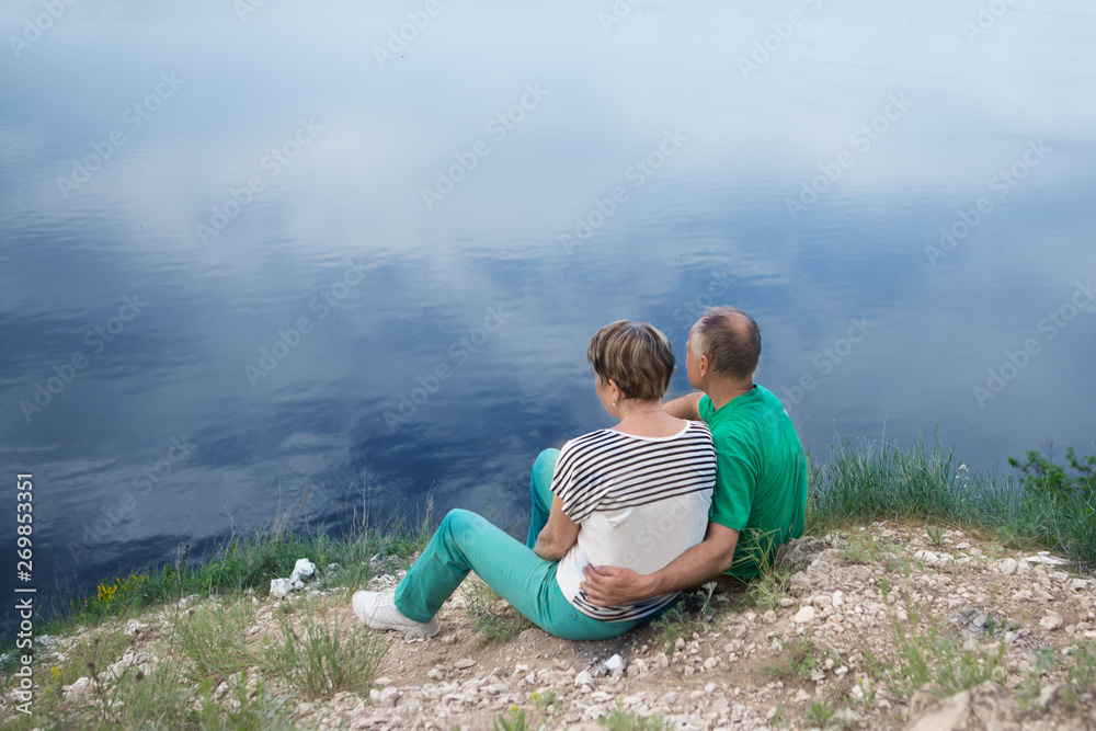 elderly couple with backpacks sits on the mountain. Senior couple walking in nature