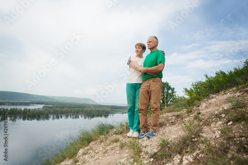 elderly couple on the top of mountain with hands up. Senior couple walking in nature