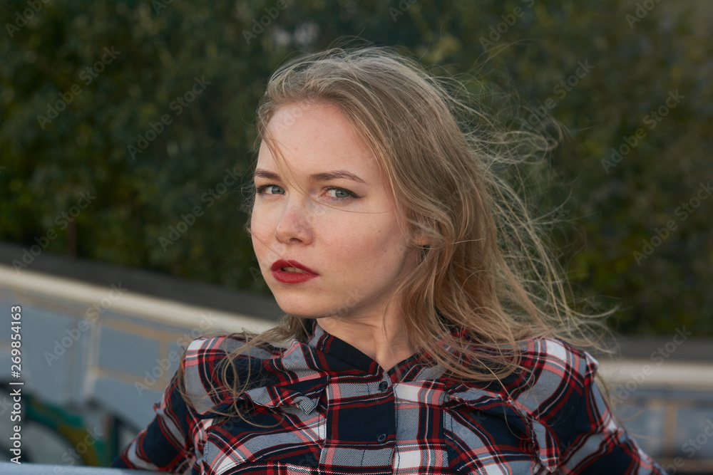 Blonde in a plaid shirt in windy weather on railway tracks. Blonde in a plaid shirt in windy weather on railway tracks.