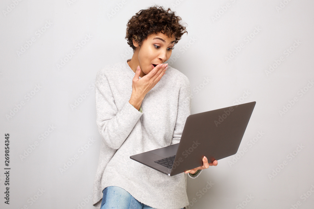 young woman with surprised expression when looking at laptop computer young woman with surprised expression when looking at laptop computer