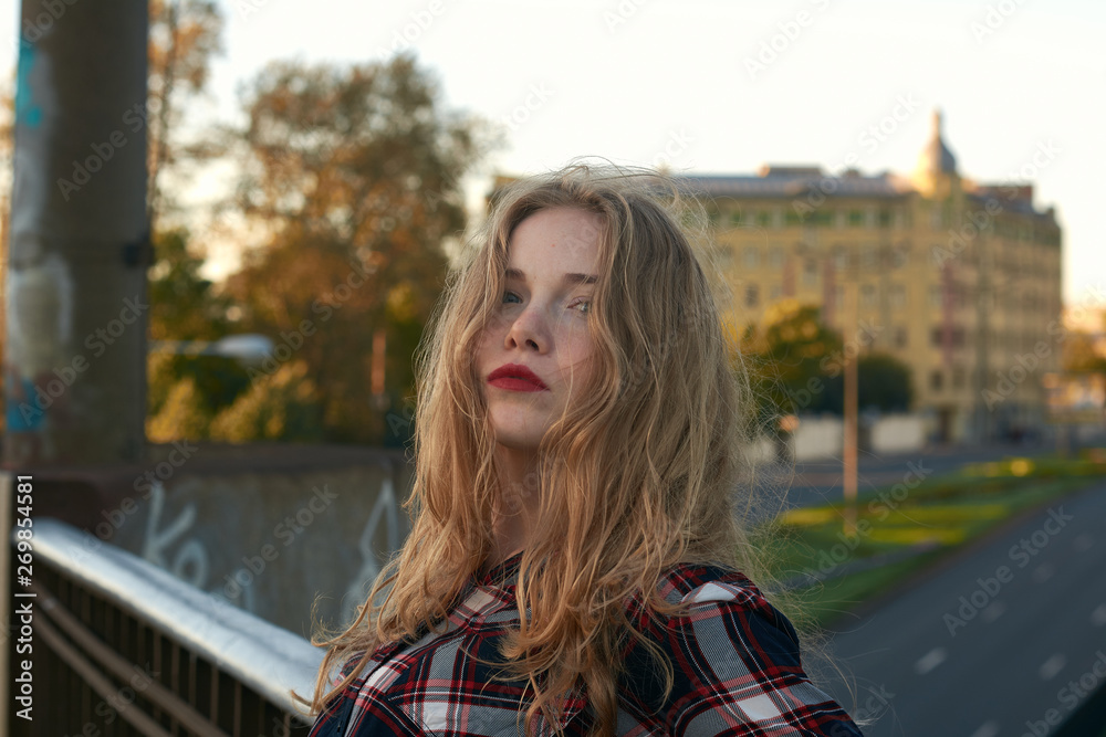 Blonde in a plaid shirt in windy weather on railway tracks. Blonde in a plaid shirt in windy weather on railway tracks.