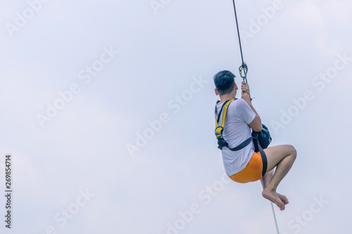 A male tourist flying on a zipline aka flying fox across the lake at Pattaya Floating Market, Thailand. © JinnaritT