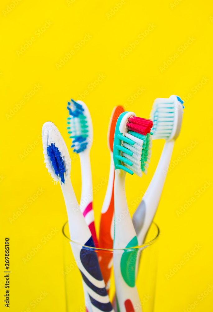 Toothbrushes in glass on yellow background Toothbrushes in glass on yellow background