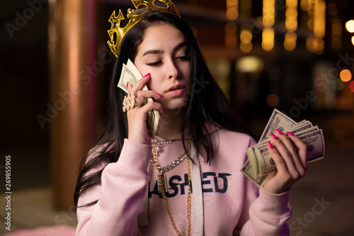Rich bitch in crown play with dollars money at night city like queen
