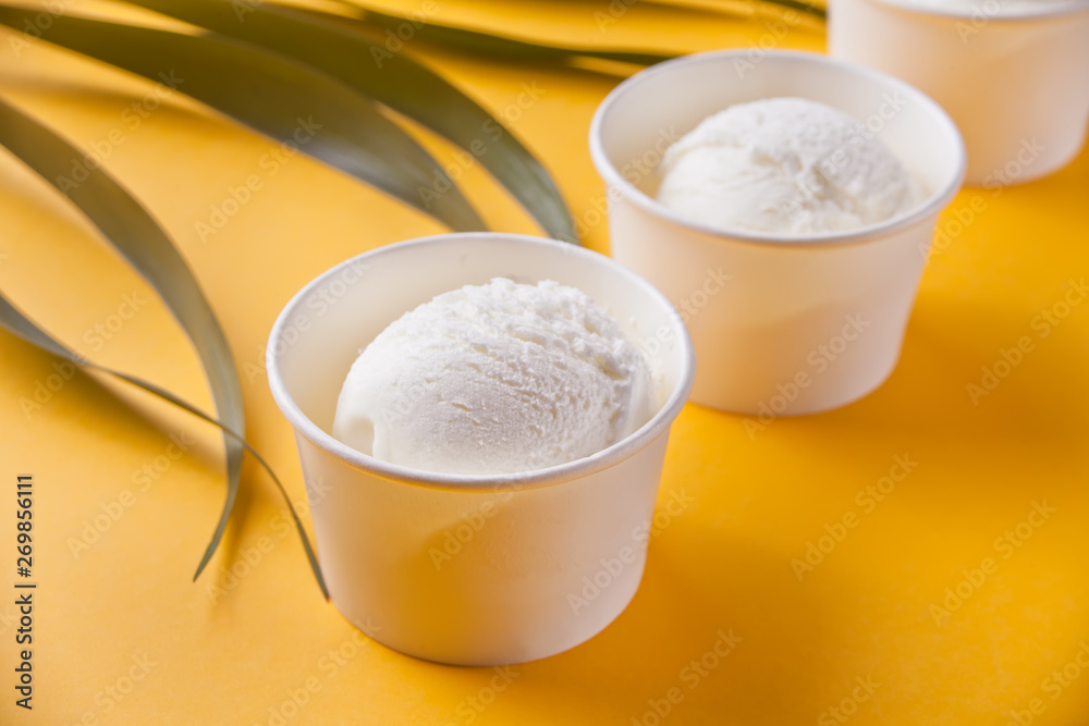 Row of vanilla ice cream and palm leaf on the yellow background Row of vanilla ice cream and palm leaf on the yellow background