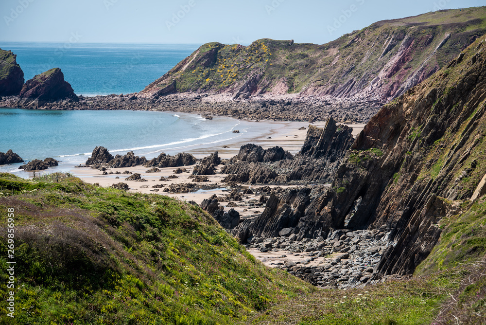 Wild rugged beach on a sunny day at low tide. With cliffs behind. Marloes Sands, Pembrokeshire. UK