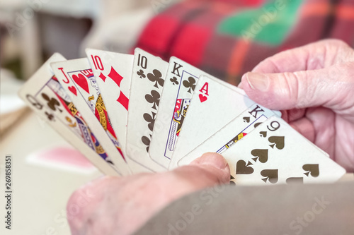 Elderly man hands holding playing cards shallow depth of field Close up shot