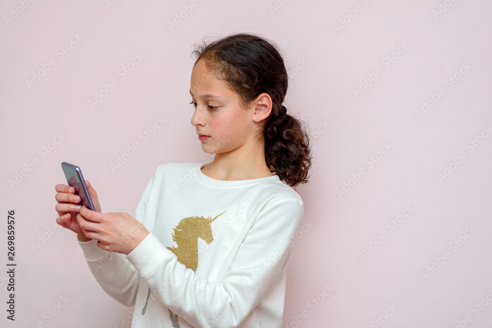 Beautiful young girl using modern smartpone, hipster child blogger typing text message on her cellphone. Beautiful young girl using modern smartpone, hipster child blogger typing text message on her cellphone.