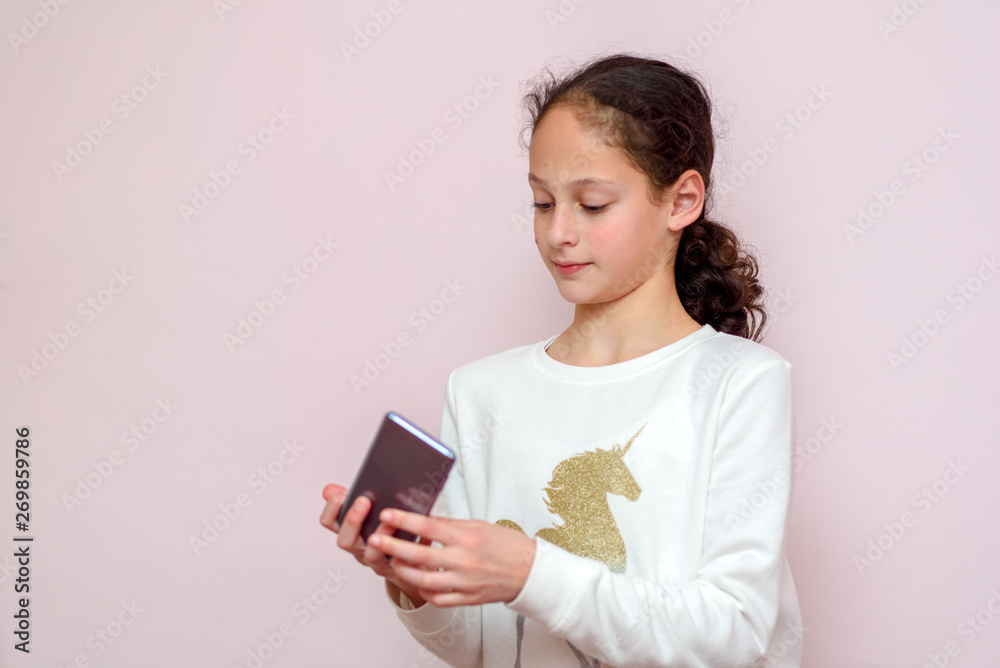 Attractive hipster teenager girl with mobile phone against pink copy space background for content or text message, chatting telephone. Attractive hipster teenager girl with mobile phone against pink copy space background for content or text message, chatting telephone.