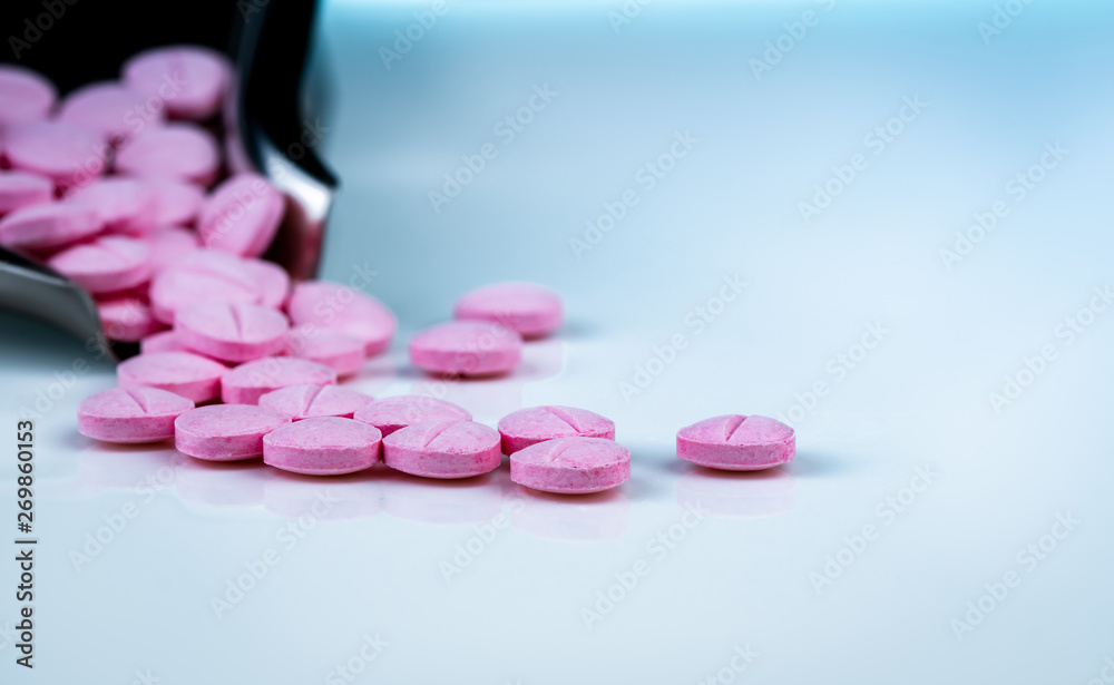 Pink tablets pills on blurred background of drug tray. Pharmaceutical industry. Pharmacy products. Vitamins and supplements. Medication use in hospital or drugstore. Global drug retail market.