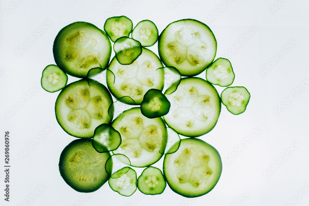 green translucent slices of cucumber on the background of bright white light close-up. transparent discs of vegetables. texture of kaleidoscope patterns in macro green translucent slices of cucumber on the background of bright white light close-up. transparent discs of vegetables. texture of kaleidoscope patterns in macro