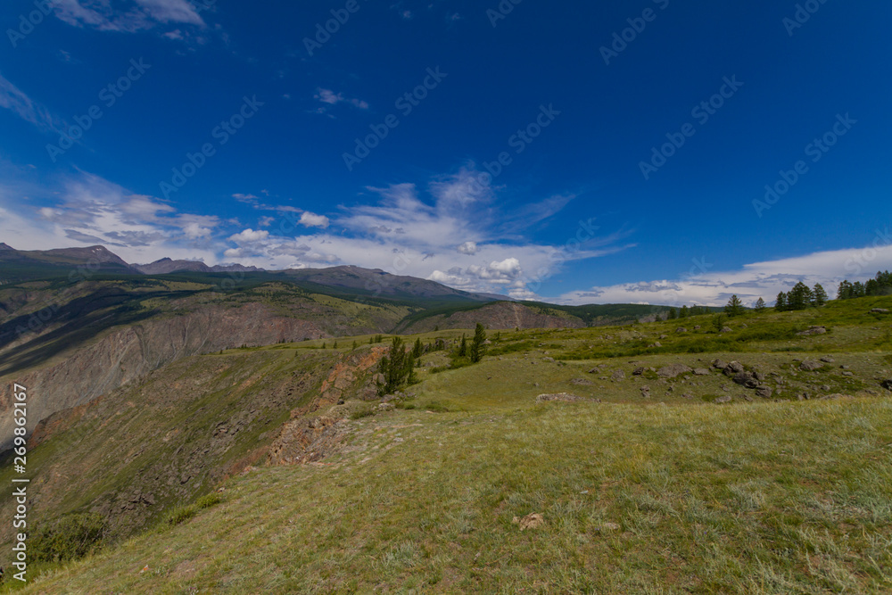 Mountain valley. Blue sky and white clouds. Summer sunny day.
