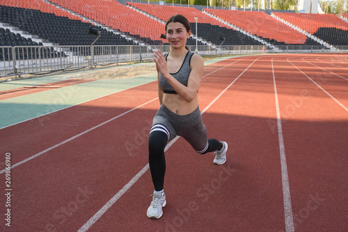 Beautiful athletic girl warming up before a hard workout at the stadium