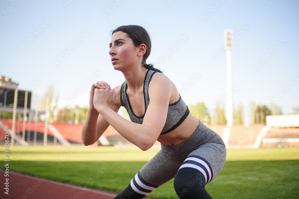 Beautiful athletic girl warming up before a hard workout at the stadium Beautiful athletic girl warming up before a hard workout at the stadium