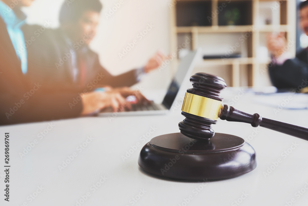Wooden gavel on table in lawyer's office. Lawyer having team meeting with the client. Concepts of law, advice, legal services. Wooden gavel on table in lawyer's office. Lawyer having team meeting with the client. Concepts of law, advice, legal services.