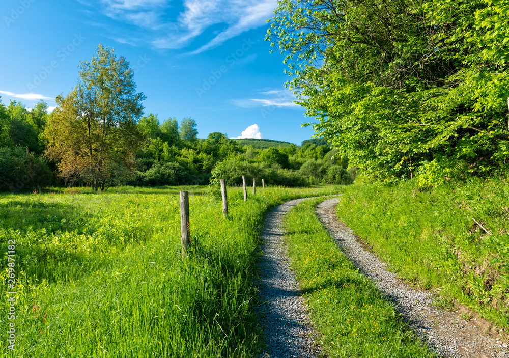 Small mountain road with blue sky and green hills with grass Small mountain road with blue sky and green hills with grass