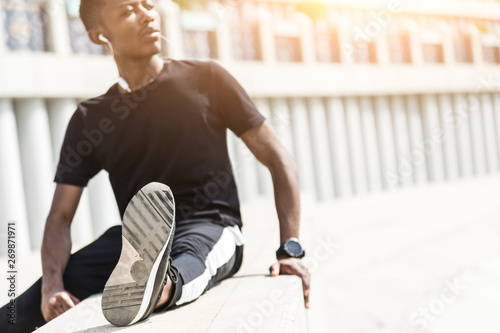 Athletic young afroamerican runner doing warm up on the promenade. Black Male running on outdoors. Healthy lifestyle concept.