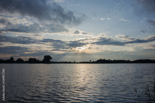 Sun behind the clouds and reflecting light in the water of the lake