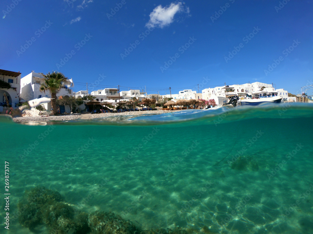 Underwater sea level photo of idilic pebble beach of Karavostasis, picturesque port of Folegandros island with traditional fishing boats docked and crystal clear turquoise sea, Cyclades, Greece
