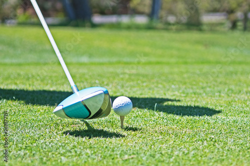 A golfer is about to strike at a ball sitting on a tee.