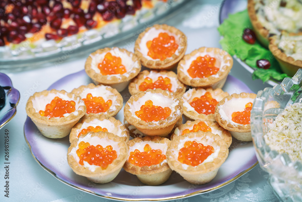 Tartlets with red caviar on a plate.