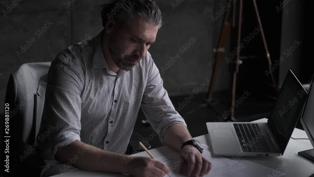 confident middle-aged man working sitting at the table in the office. confident middle-aged man working sitting at the table in the office.