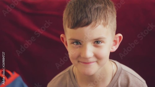 Portrait of teen boy looking at camera and smiling. Burgundy background photo