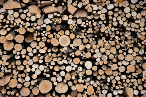 Stack of air-dried  home-made  hardwood firewood. A wall of wooden logs that form a background design.