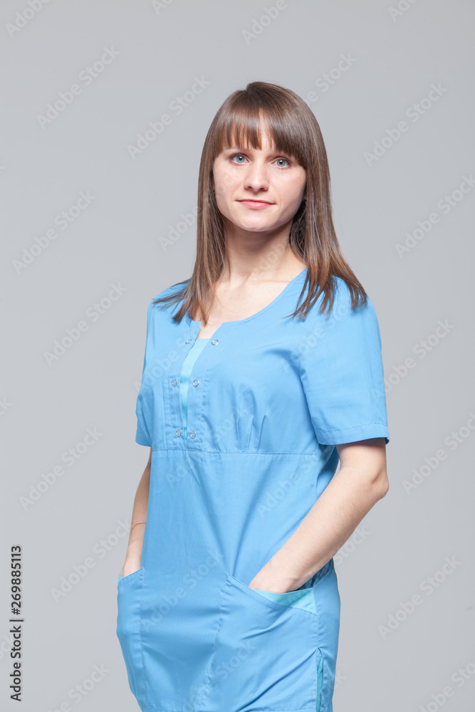 Portrait of young female doctor standing in blue uniform Portrait of young female doctor standing in blue uniform