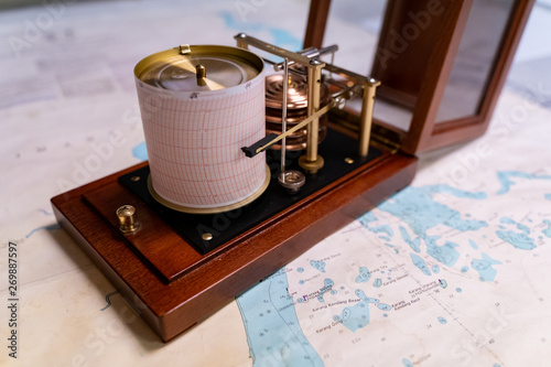 Vintage marine barograph with opened cover standing on a navigational chart