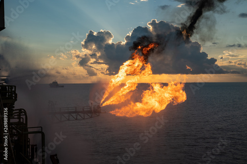 Well testing operation (flaring) of an oil and gas drilling rig. Burning huge gas flame controlled by the deluge system