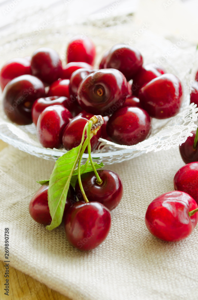Bright juicy red berries and leaves of sweet cherry in a small glass bowl. Close-up, selective focus image. Bright juicy red berries and leaves of sweet cherry in a small glass bowl. Close-up, selective focus image.