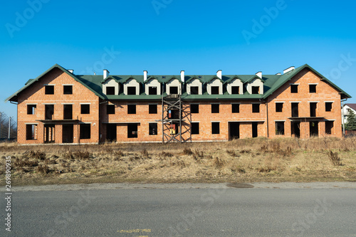 big house under construction from red brick. Unfinished two-story house