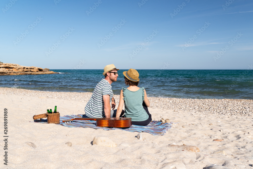 Couple in love enjoying a romantic picnic with music at a mediterranean beach. Love and travel