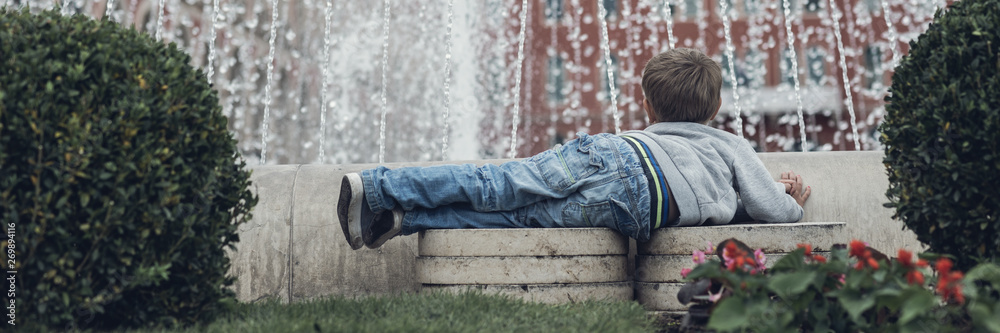 Toddler boy lying in front of a water fountain Toddler boy lying in front of a water fountain