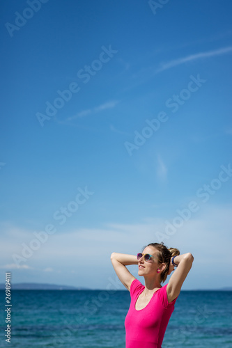 Young woman in pink shirt standing by the sea